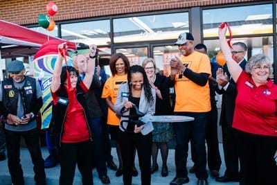 Group of people celebrating the opening of a 7-Eleven franchise.