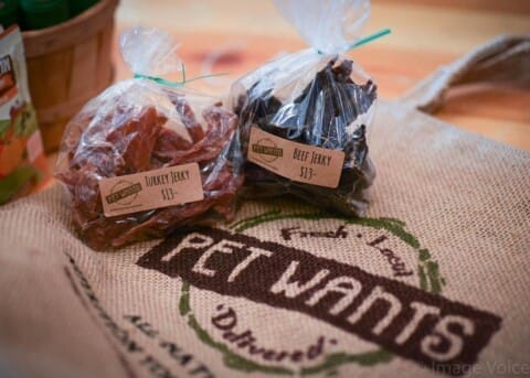 Two bags of Turkey and Beef jerky placed on a burlap sack with "Pet Wants" printed on it.
