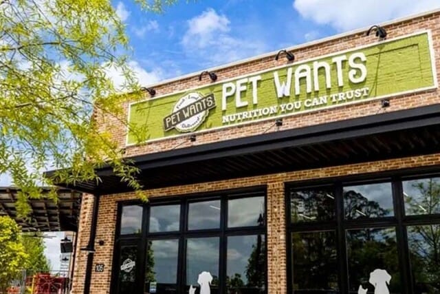 Front view of a "Pet Wants" store with a green sign displaying the brand logo and slogan.