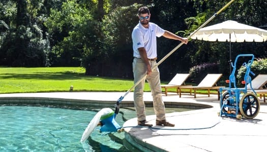 A franchisee cleaning a pool for America's Swimming Pool Company with a long handled net.