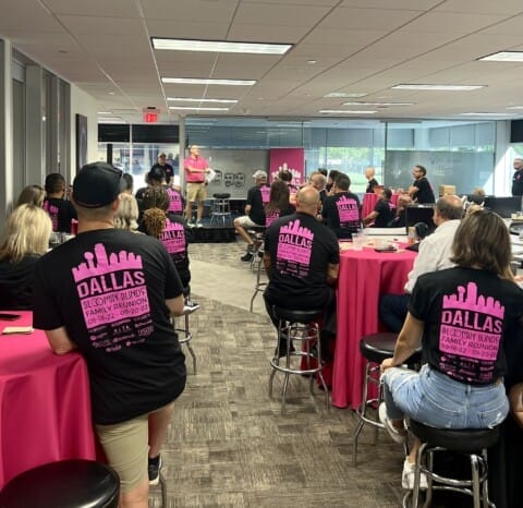 Group of franchisees wearing matching pink t-shirts at a Bloomin' Blinds community meeting or event.