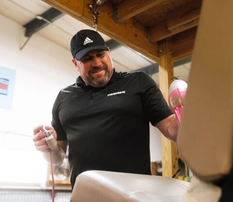 A Fibrenew franchisee in a black cap and branded shirt restores furniture covering.