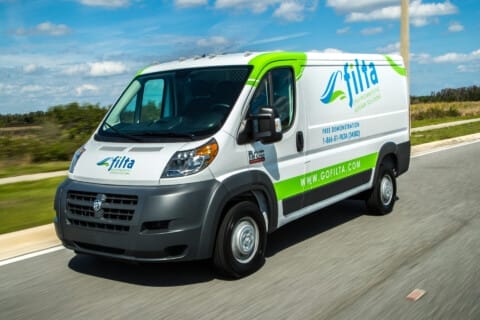 A company van with "Filta" branding, known for its filtration services, driving on a highway under a clear sky.