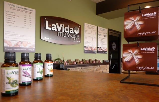 The serene spa reception area features LaVida Massage signage and essential oils neatly arranged on the counter.