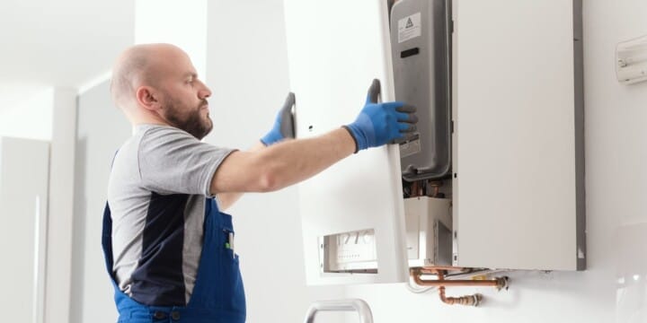 A Home Service technician servicing a wall-mounted gas heating boiler.